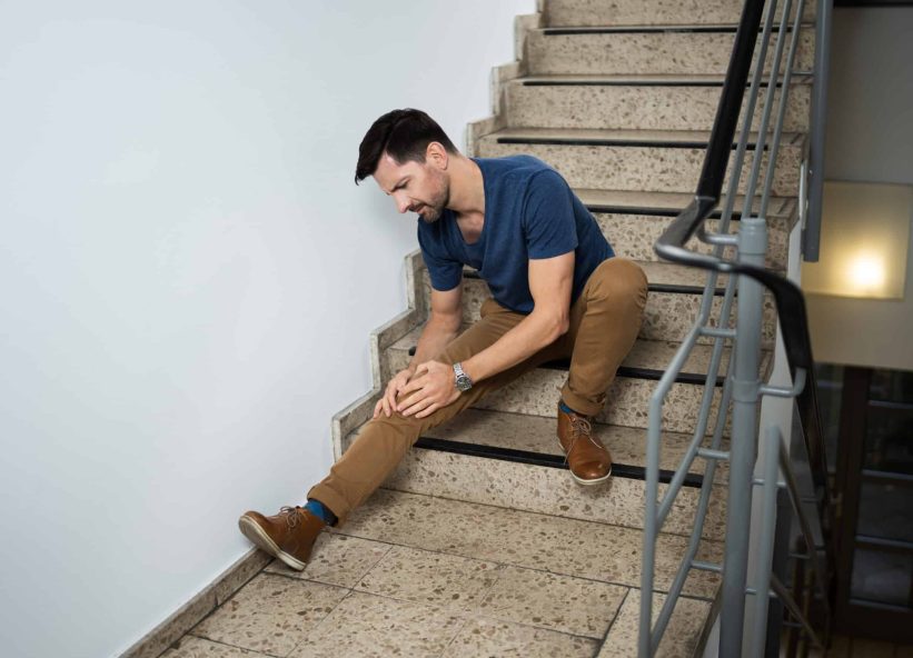 Man Sitting On Staircase After Slip And Fall Accident